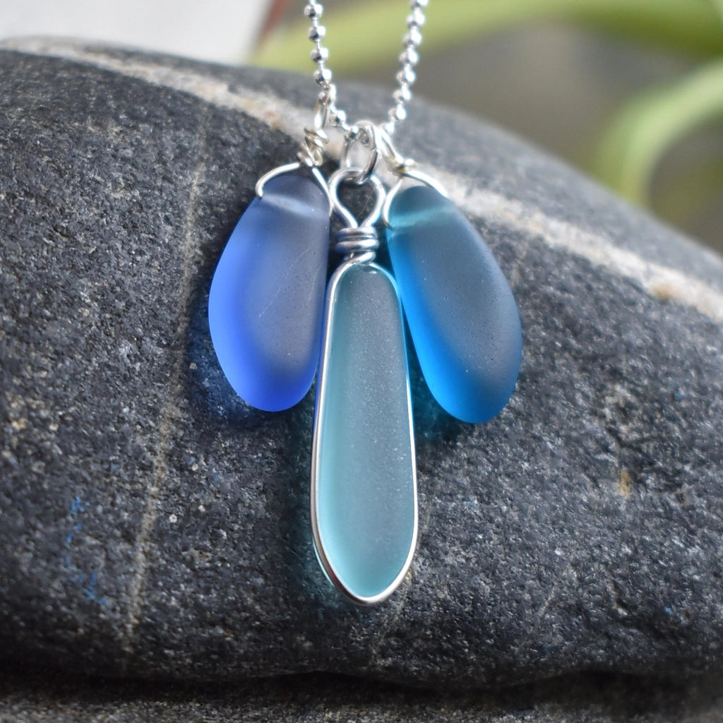 Blue glass pendant necklace on a dark stone surface
